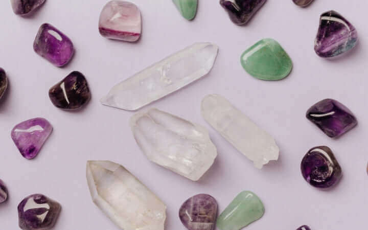 Various colored healing crystals including amethyst, rose quartz, and jade on a white background, showcasing their natural beauty.