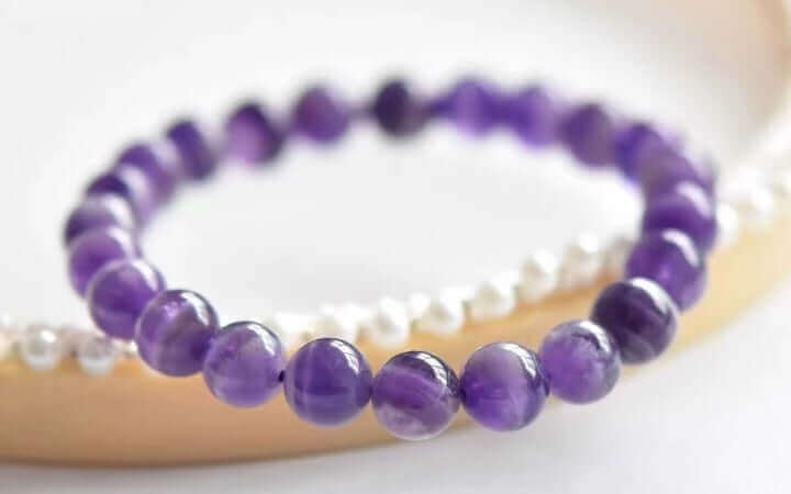 Amethyst bead bracelet on display, showcasing vibrant purple hues and smooth polished finish.