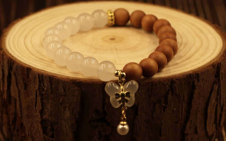 Feng Shui bracelet featuring wooden and white beads with a butterfly charm, symbolizing balance and harmony.