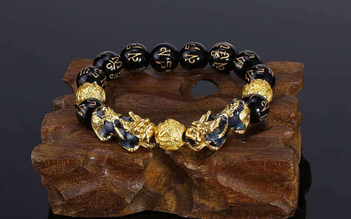 Feng Shui bracelet with gold dragon design on black beads, displayed on a wooden surface