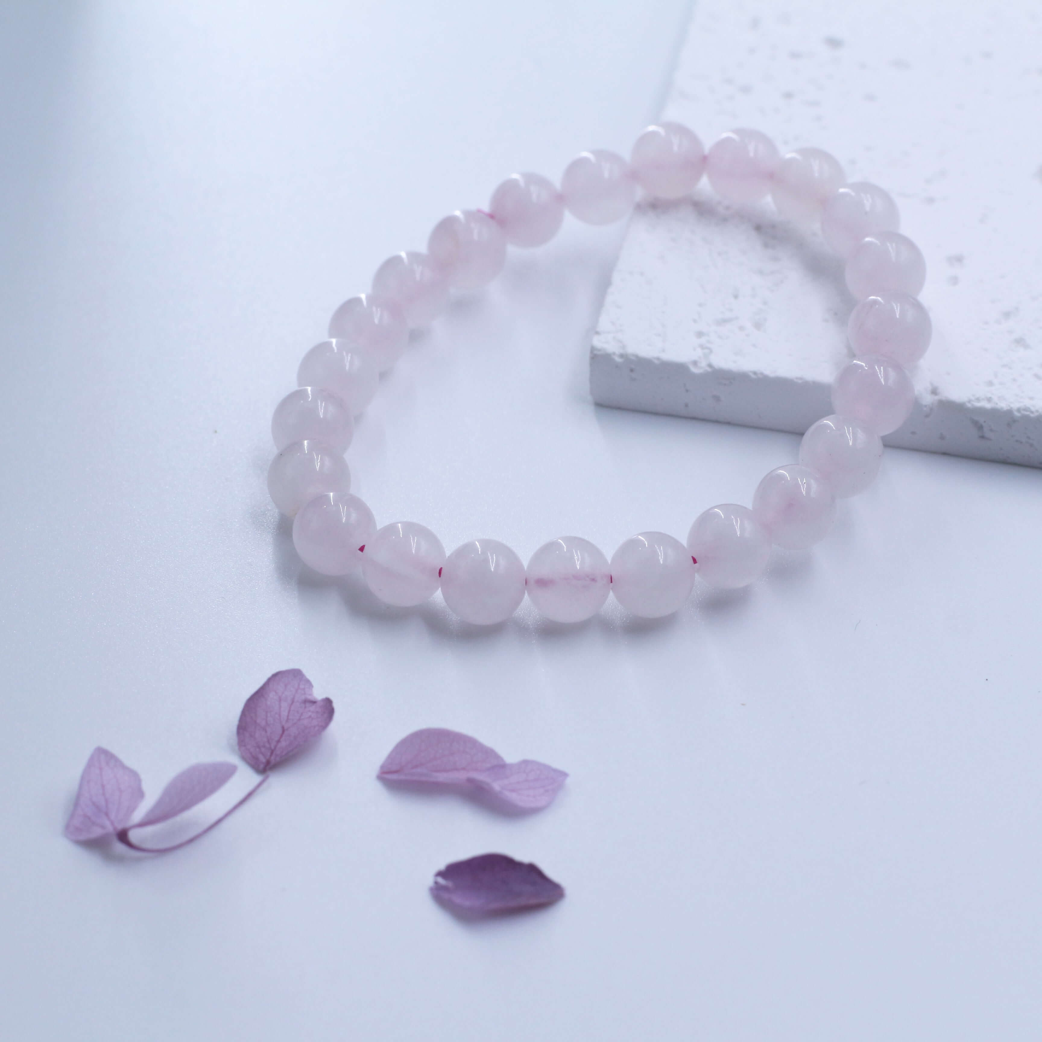 Romantic Rose Quartz Bracelet for love and relationships, featuring delicate pink crystals on a neutral background with petals.