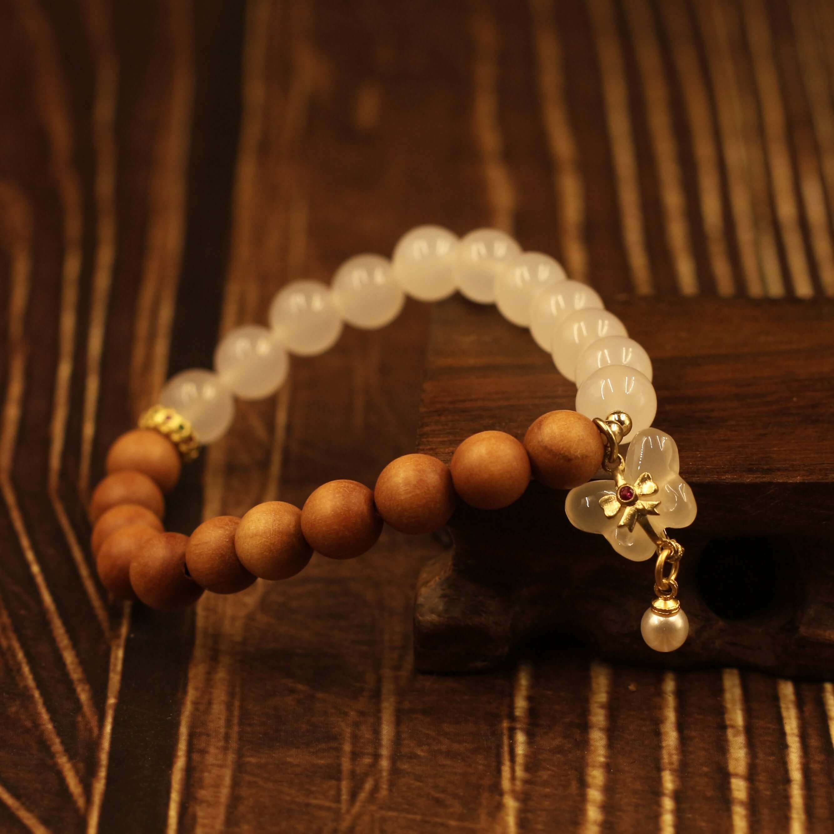 Double Purifying Butterfly Tassel Bracelet on wood surface, featuring Barbie sandalwood beads for clarity and new life.