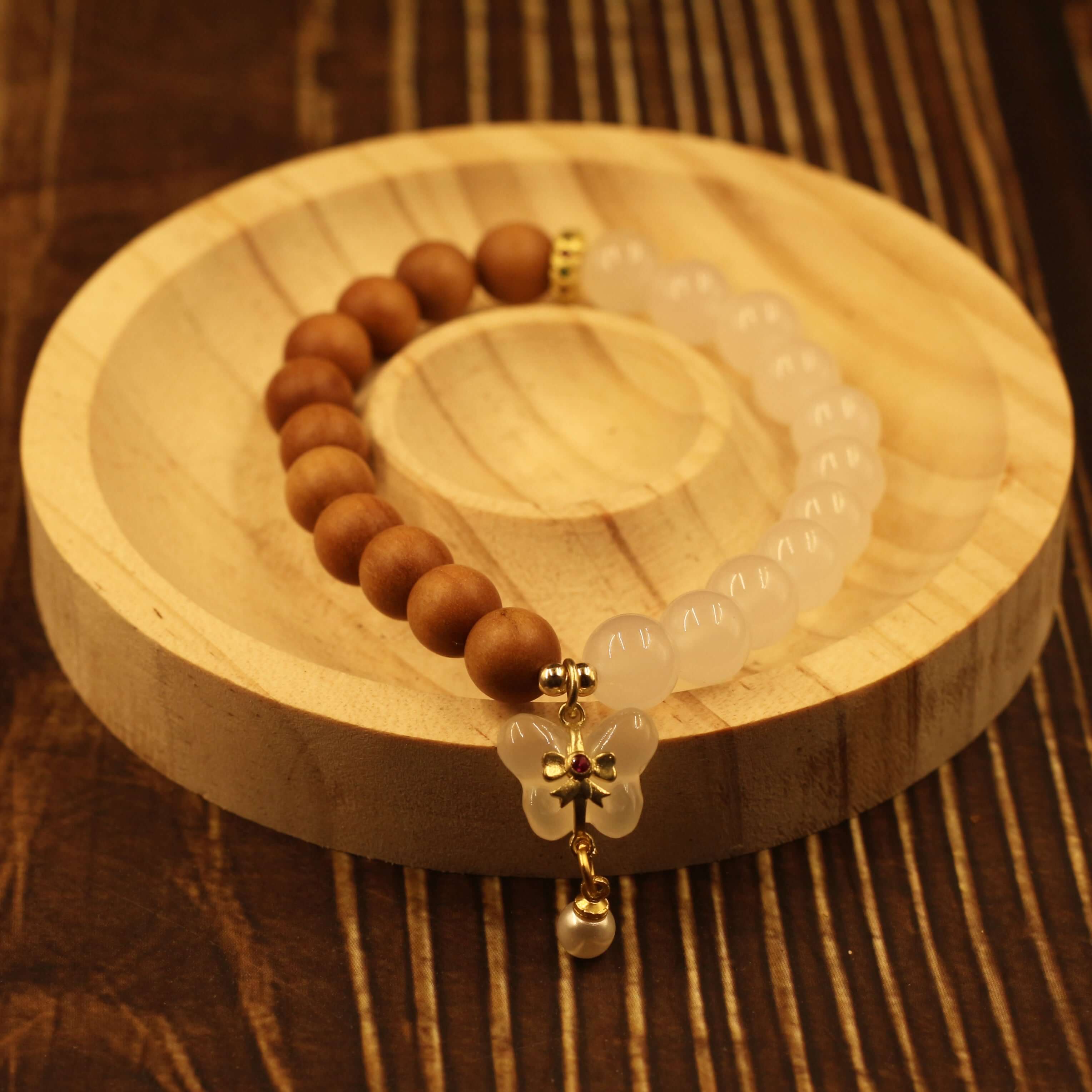 Double Purifying Butterfly Tassel Bracelet with Barbie sandalwood beads on wooden tray, symbolizing clarity and new life.