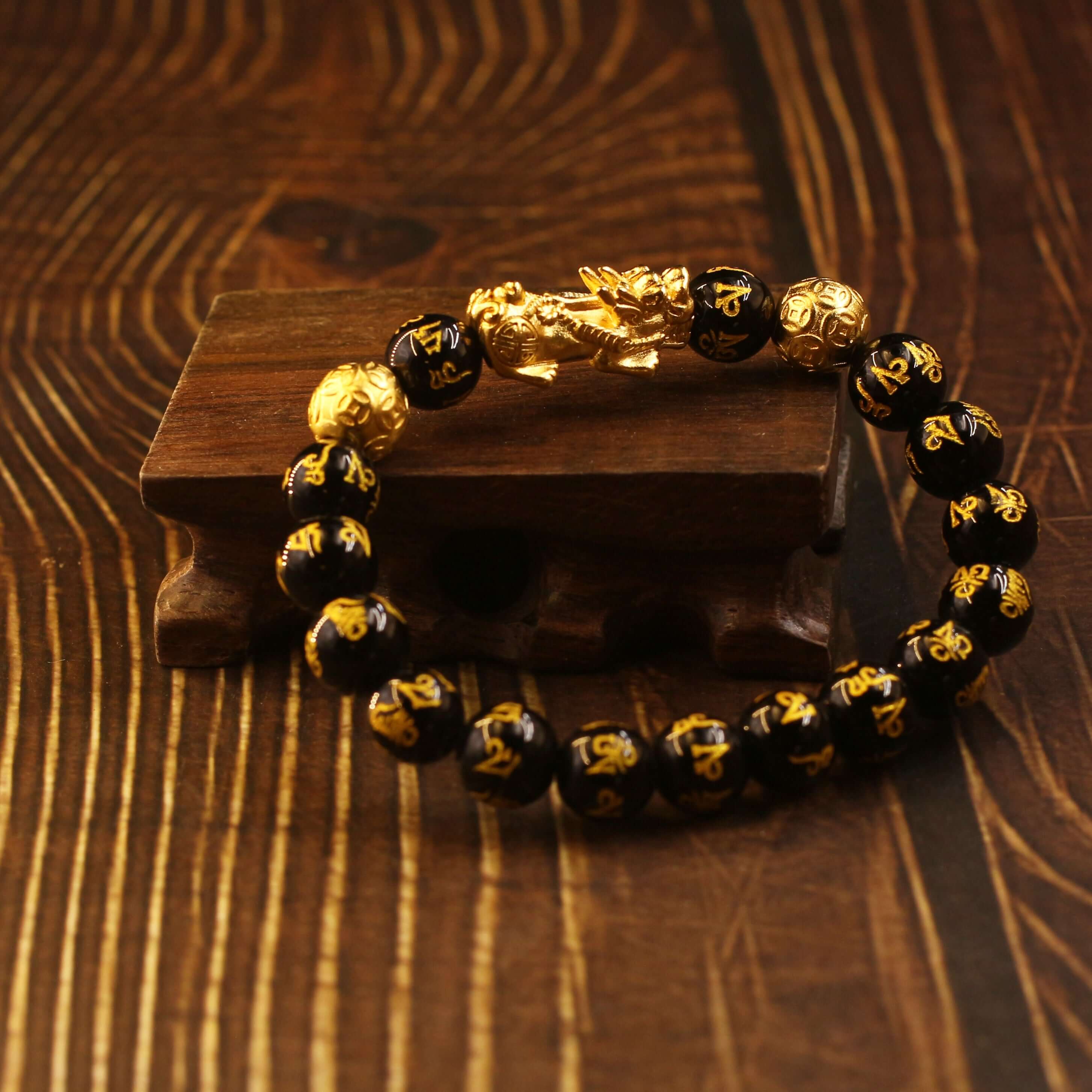 Classic Feng Shui Bracelet with Pixiu and Black Obsidian beads for wealth on wooden background.